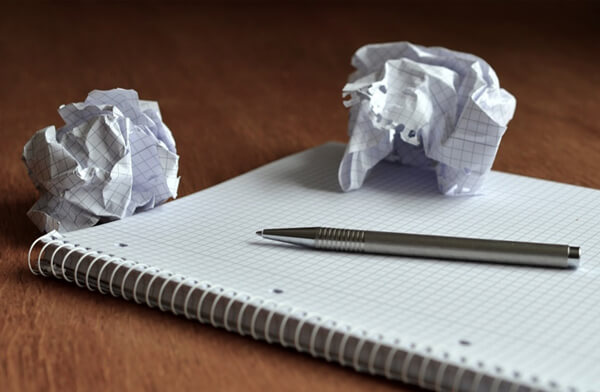 Caderno e caneta para planejamento com folhas amassadas representando ideais descartadas! Respostas rápidas a mudanças.