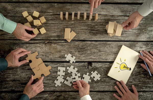 Foto de mesa com diversos elementos sendo sugeridos por diversas pessoas, como se fossem ideias que juntas serão melhores do que isoladas